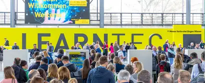 Menschenmenge am Eingang der LEARNTEC 2025 in Karlsruhe vor gelber Wand mit Schriftzug