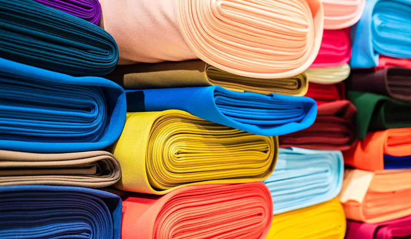 Stapel bunter Stoffrollen symbolisieren vielfältige Produktvarianten in der Konfiguration.