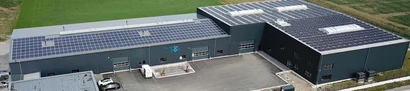 Luftaufnahme Fischer-EKF-Firmengebäude mit Solaranlagen auf dem Dach & Parkplatz umgeben von Feldern