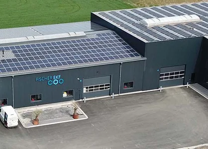 Luftaufnahme Fischer-EKF-Firmengebäude mit Solaranlagen auf dem Dach & Parkplatz umgeben von Feldern