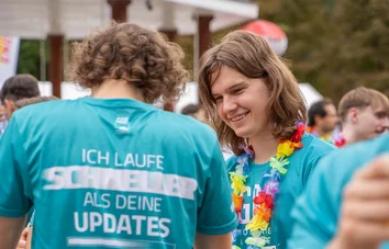Junge Männer mit bunten Blumenketten unterhalten sich lachend beim RUN & FUN in Krefeld 2025