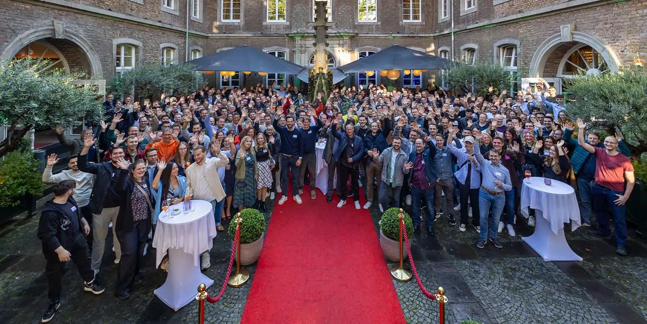 Team GOB in weißen T-Shirts versammelt in grüner Landschaft und fröhlich in die Kamera winkend