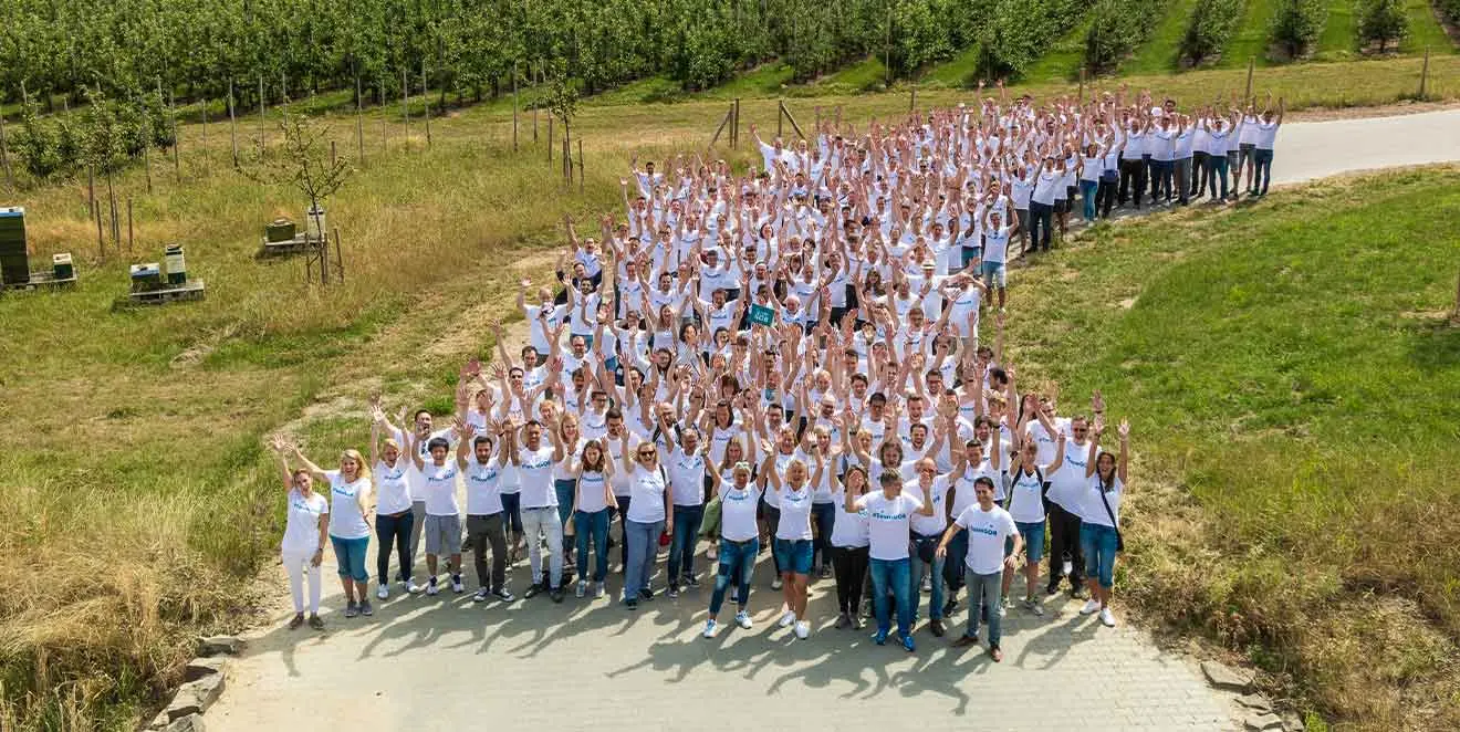 Team GOB in white T-shirts gathered in a green landscape and waving cheerfully into the camera