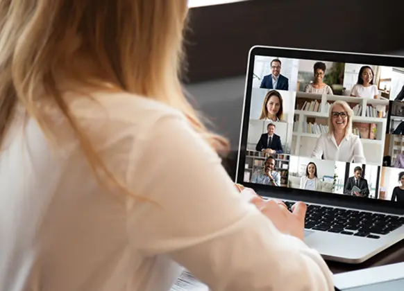 Frau vor Laptop in virtuellem Meeting.