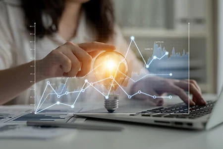 Symbolbild: Hand tippt am Laptop, darüber Liniengrafik und Glühbirne als BI-Idee.