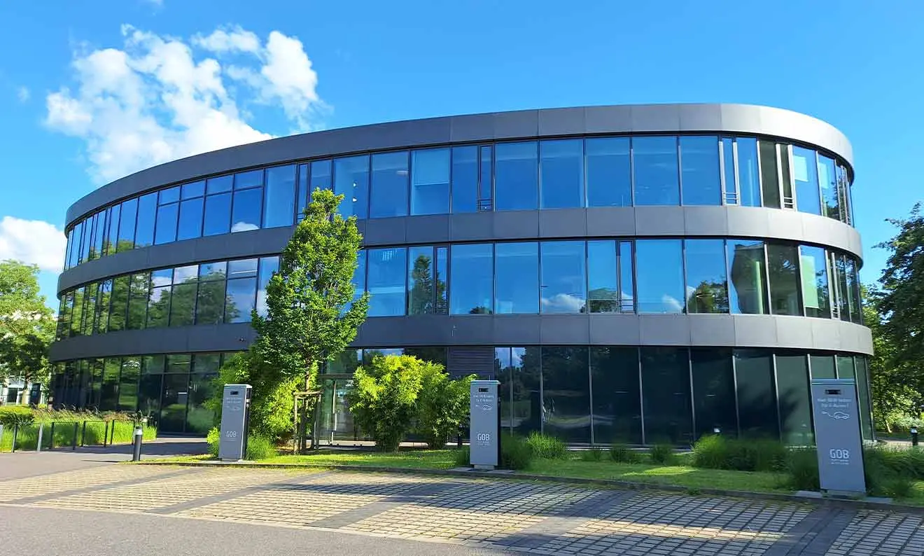 Side view of the GOB building with 3 e-charging points in the car park under a blue sky