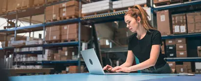 Mitarbeiterin in der Logistik arbeitet mit ERP-System am Laptop zur Lagerbestandsverwaltung.