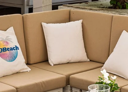 Beige Outdoor-Ecksofa mit Kissen; Aufdrucke „GOBeach“ und „GEMEINSAM STABIL WACHSEN“ sichtbar.