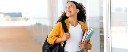 Lächelnde Studentin mit Rucksack und Büchern vor Glasfassade – Symbolbild für RUB Karrieremesse 2025