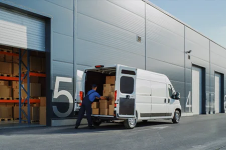 Mitarbeiter lädt Kartons in einen Lieferwagen an der Laderampe für Online- und Versandhandel.