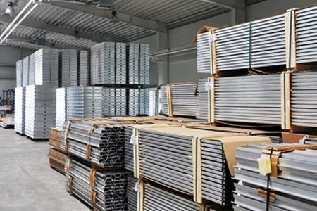 Innenansicht einer Industriehalle: Gestapelte Aluminiumprofile und Paletten