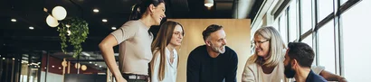 Organise collaboration and processes efficiently within clubs and associations – with unitop Symbolic image: Five people are standing together, laughing in a bright office with large windows.