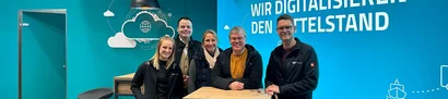 GOB-Stand auf LogiMAT 2024 | 1920 x 780 Pixel LogiMAT 2024: Fünf Personen am GOB-Stand vor blauer Wand mit „Wir digitalisieren den Mittelstand“