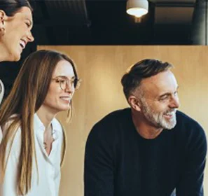 Zusammenarbeit und Prozesse in Vereinen und Verbänden effizient organisieren – mit unitop Symbolbild für Vereinsarbeit: Vier Personen stehen zusammen und lachen in einem hellen Büro.
