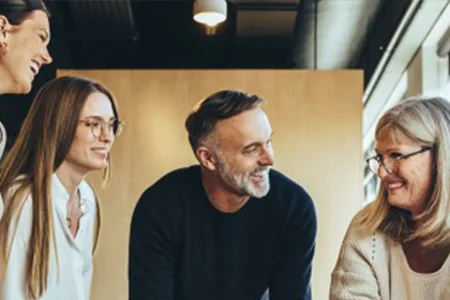 Zusammenarbeit und Prozesse in Vereinen und Verbänden effizient organisieren – mit unitop Symbolbild für Vereinsarbeit: Vier Personen stehen zusammen und lachen in einem hellen Büro.