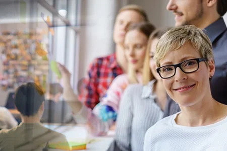 Organisation, Kurse und Prozesse im Griff – mit unserer unitop-Lösung für Bildungseinrichtungen Seminarraum: Personen arbeiten, blonde Seminarleiterin im Vordergrund.