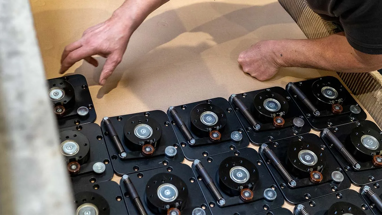 Person ordnet technische Bauteile auf Karton an Nahaufnahme von Händen, die technische Bauteile mit Federn und Lagern auf Karton anordnen
