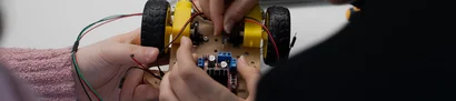 Spannende Aufgabe auf dem Girl’s Day 2024: Roboterfahrzeug bauen | 1905 x 425 Pixel Schülerin & Schüler arbeiten an einem Roboter-Fahrzeug, Laptop auf dem Tisch