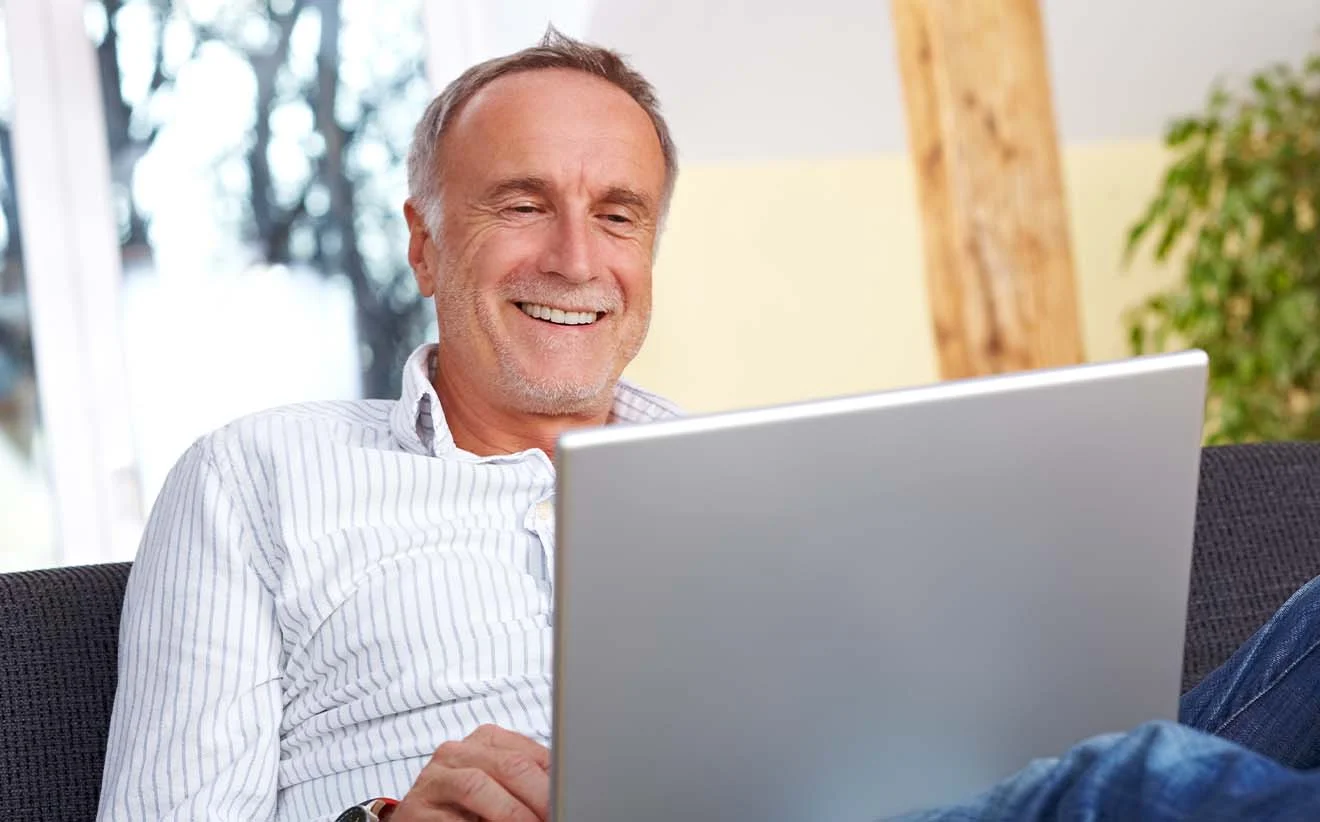Older man uses a solution to manage the DASBV employers’ notification procedure on his laptop.
