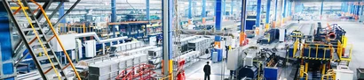 Große, helle Produktionshalle mit modernen Maschinen, Fördertechnik und Fertigungslinien.