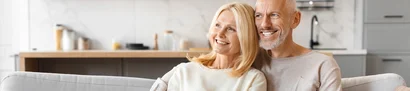 A relaxed retired couple enjoys a carefree retirement on the sofa thanks to good pension provision.