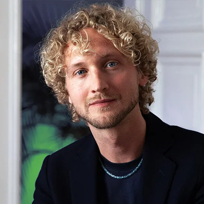 Christian Uhle – Philosoph und Zukunftsforscher Porträt von Christian Uhle, Philosoph und Zukunftsforscher, mit lockigem Haar, Blick zur Kamera.