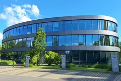 Side view of the GOB building against a blue sky, with e-charging points at the car park