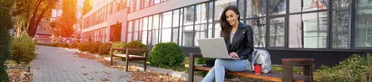 Junge Frau mit Laptop vor moderner Kulisse – Symbolbild für das KMS Ausbildungsforum 2026 in Krefeld