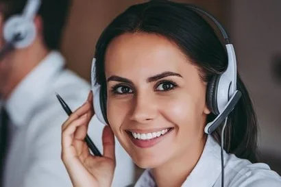 Exclusive services for customers – with dedicated contact persons Woman with headset smiling friendly at the camera, two call centre agents working in the Background