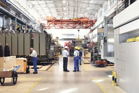 Employees in a modern production hall with large machines and structured work areas.