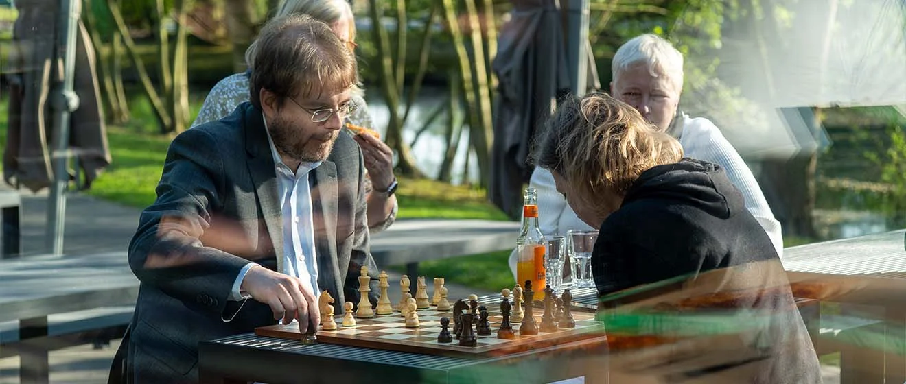 Sundowner April 2026 – Austausch im Freien nach dem Vortrag Sundowner April 2026: Gäste spielen Schach auf der Terrasse, Getränke auf dem Tisch.