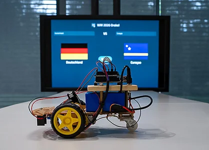 KI trifft Arduino beim WM-Orakel Arduino-Roboter steht vor einem Bildschirm mit dem WM-Orakel 2026.