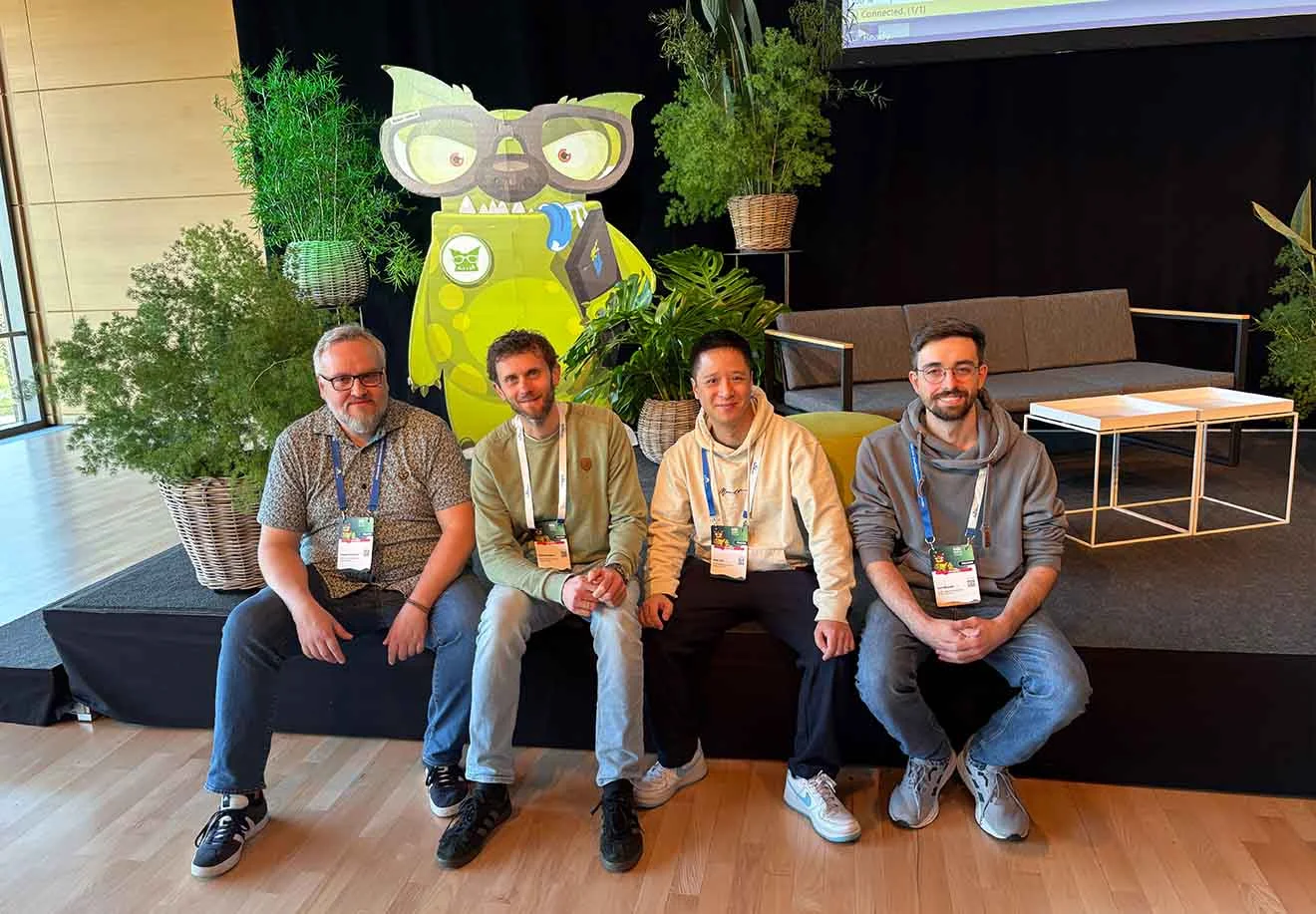 Vier Teilnehmende sitzen vor Pflanzen, dahinter eine Datamonster-Figur auf der SQL-Konferenz 2026.