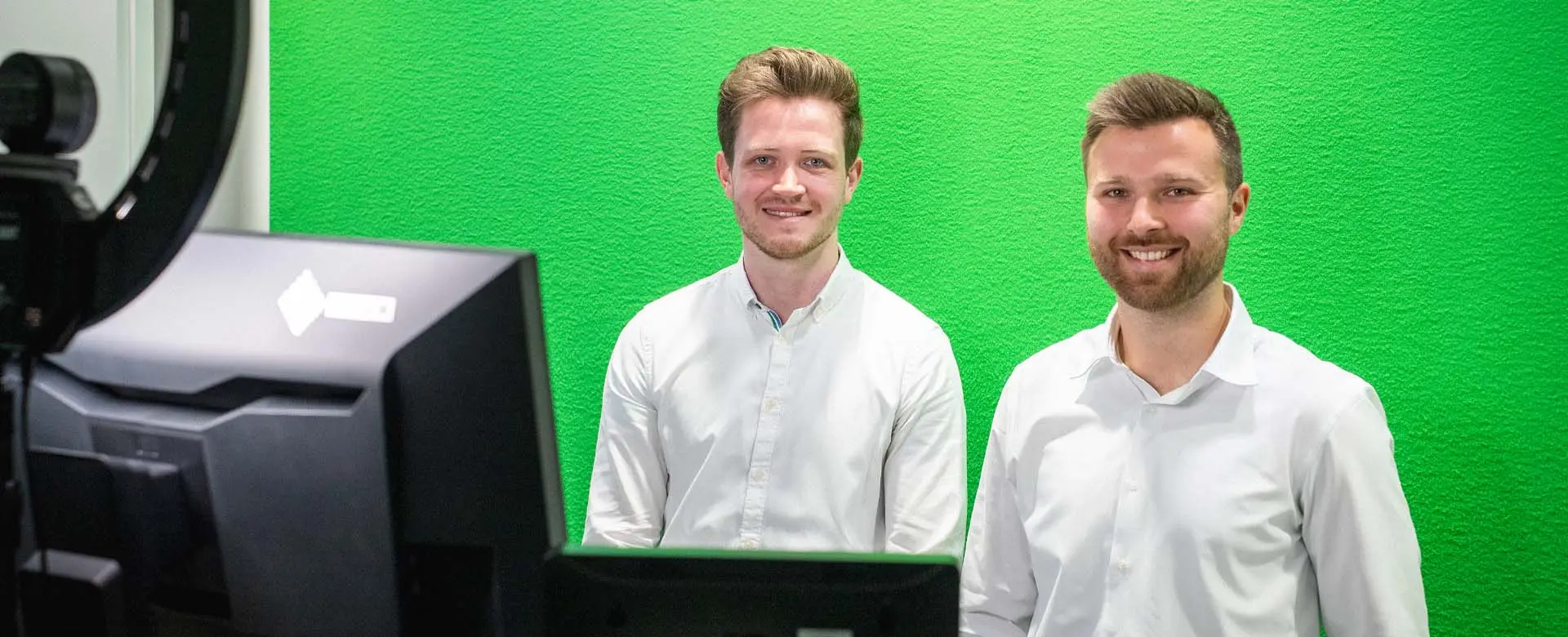 Daniel Heuhsen und Moritz Eichenauer im Webinar zu Microsoft 365 Copilot für NPOs vor grünem Screen.