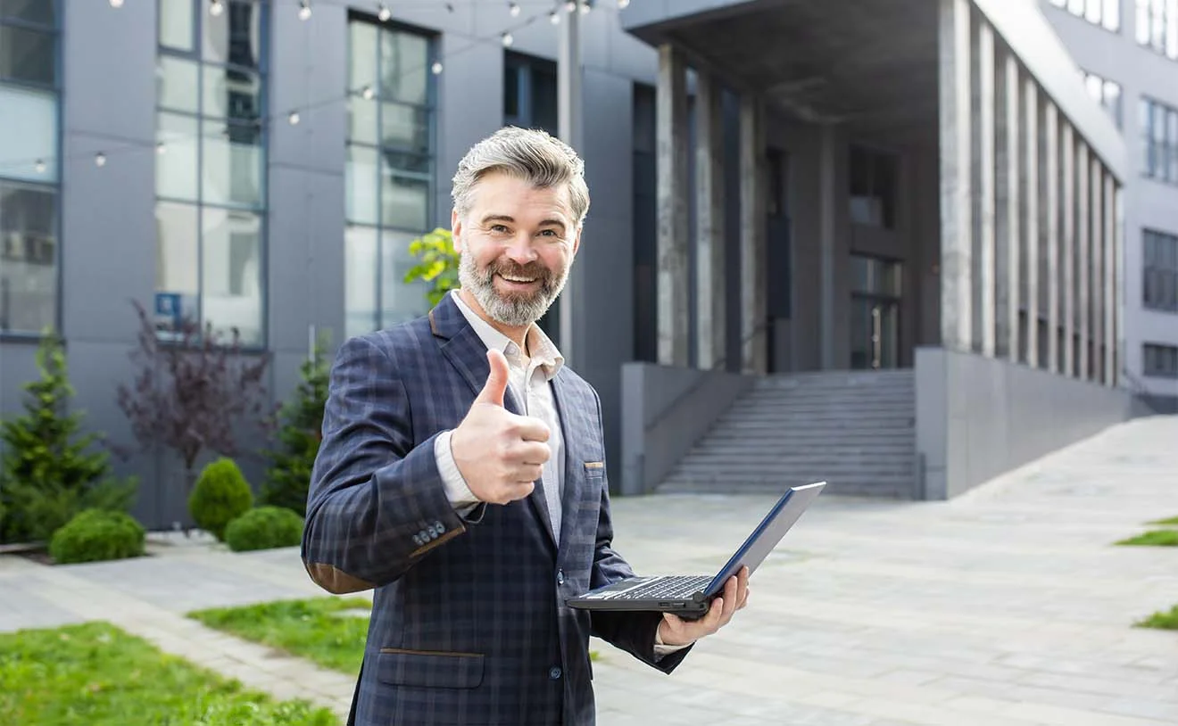 Mission accomplished: ERP erfolgreich eingeführt Geschäftsmann im Anzug zeigt Daumen hoch – Symbolbild für erfolgreiche ERP-Einführung