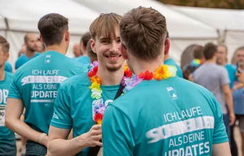 Zwei GOB-Läufer mit Blumenketten stehen am Teamzelt und unterhalten sich beim RUN & FUN 2025