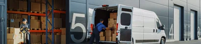 Mitarbeiter lädt Kartons in einen Lieferwagen an der Laderampe für Online- und Versandhandel.