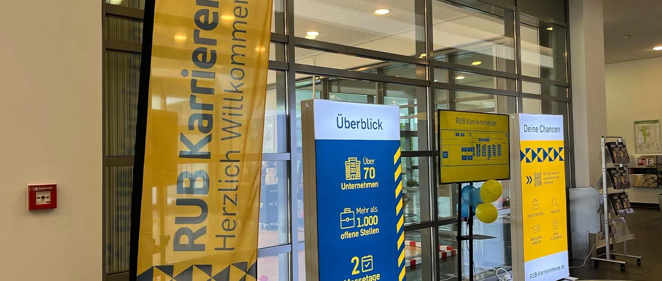 Willkommen auf der RUB Karrieremesse 2026 Eingangsbereich der RUB Karrieremesse 2026 mit gelben Wegweisern und Informationsstelen.