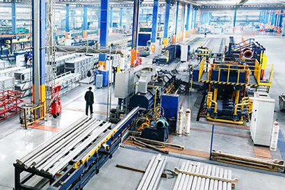 Industriehalle mit Maschinen, Förderstrecken und laufender Produktion in mittlerer Perspektive.