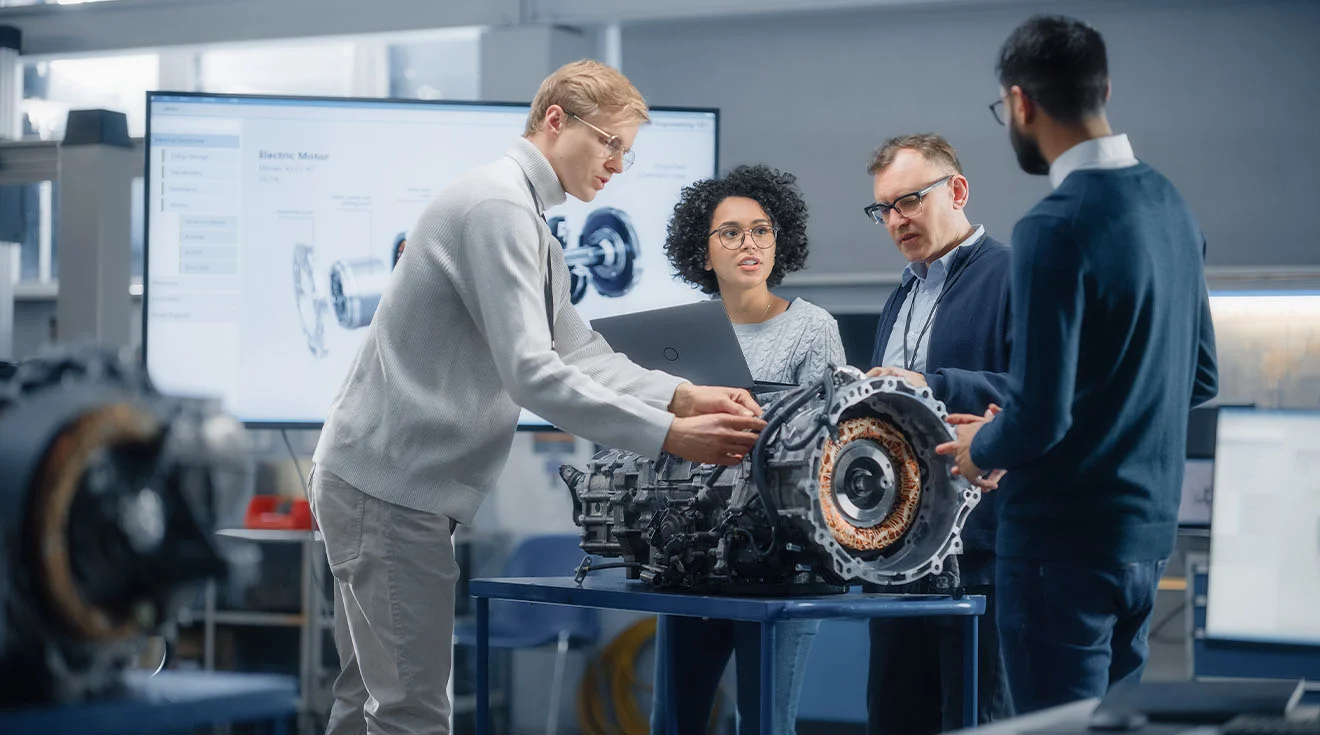Optimally managing innovative product development in mechanical engineering – with unitop Engineering team examines engine components and discusses technical details in front of a screen.