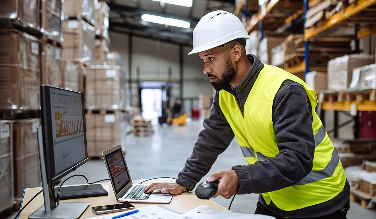 Mitarbeiter prüft Lagerbestände mit LVS und Barcodescanner im Hochregallager