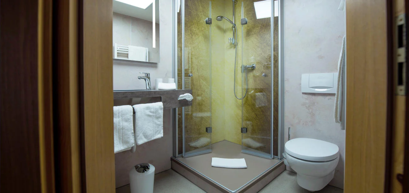 Platzsparendes Bad mit Eckeinstiegsdusche – Duschking Vertriebs GmbH Kleines Bad mit verglaster Eckeinstiegsdusche, Waschtisch und WC