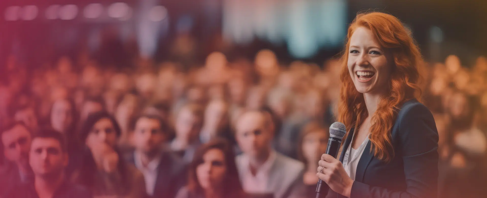 Lächelnde Rednerin mit Mikrofon spricht vor einem großen, aufmerksamen Publikum auf einer Konferenz