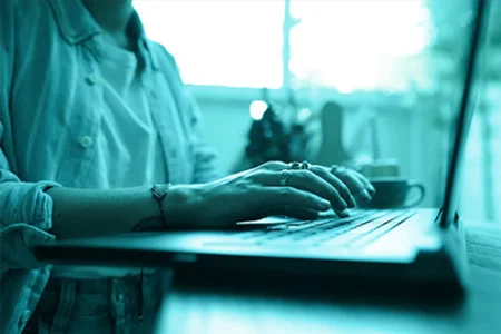 unitop Learning in practice: browse through knowledge documentation and learn on your own! Person types on laptop in a concentrated manner and researches in a relaxed atmosphere