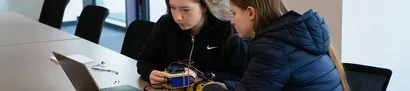 Girls’Day 2025: Programmierung von Arduino-Roboter | 1905 x 425 Pixel Zwei Teilnehmerinnen des Girls'Day 2025 programmieren einen Arduino-Roboter gemeinsam am Laptop