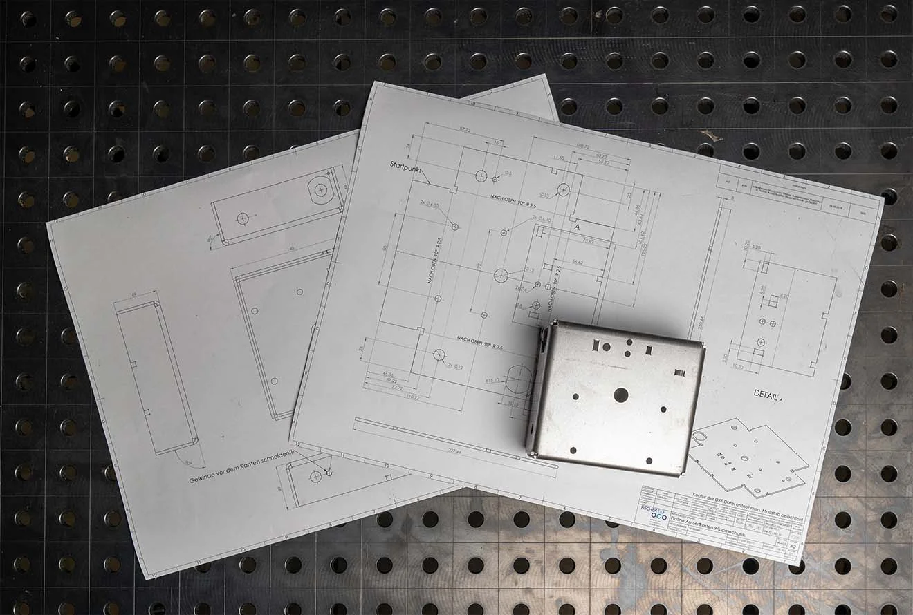 Technische Zeichnungen Fischer EKF Technische Zeichnungen mit Präzisionsmaßen & ein passendes Metallbauteil auf gelochter Arbeitsfläche
