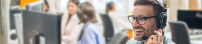 Lächelnder IT-Service-Mitarbeiter mit Headset hilft Kunden