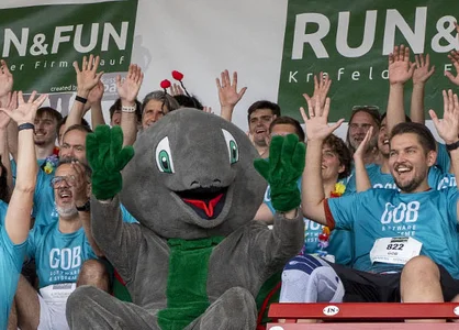 GOB-Teamfoto auf der Tribüne der Krefelder Galopprennbahn | RUN & FUN 2025 Das GOB-Team jubelt auf der Tribüne der Galopprennbahn neben dem RUN & FUN-Maskottchen