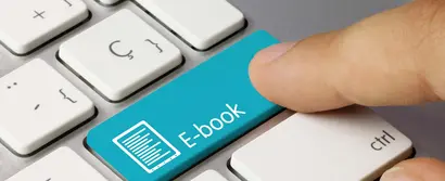 Nahaufnahme einer Computertastatur mit blauem E-Book-Button und darauf zeigendem Finger