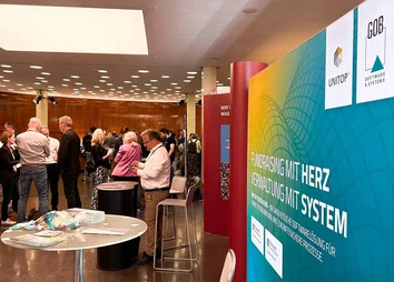 GOB-Infostand auf dem DFK 2025 mit Teilnehmenden im Gespräch und Infomaterialien im Vordergrund